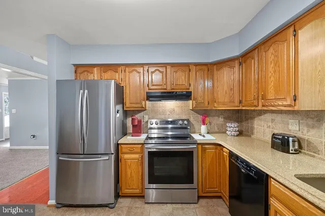 a kitchen with stainless steel appliances granite countertop a sink dishwasher a stove and a dining table with wooden floor
