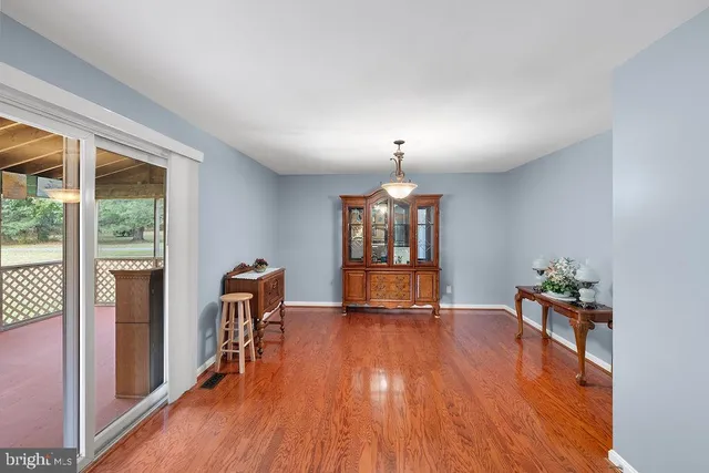 an empty room with chandelier fan and windows