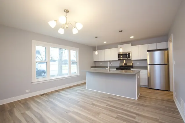 a open kitchen with kitchen island a sink dishwasher a refrigerator and a stove with wooden floor