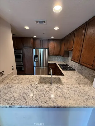 a kitchen with granite countertop sink refrigerator and cabinets
