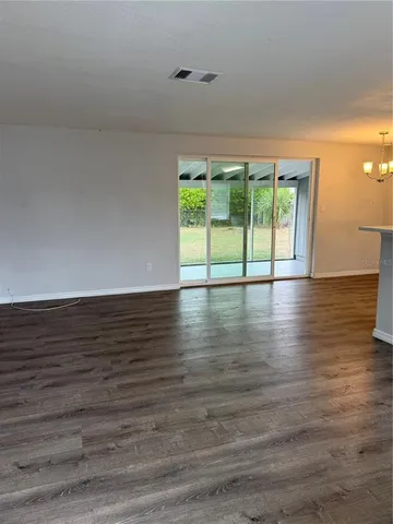 a view of an empty room with wooden floor and a large window
