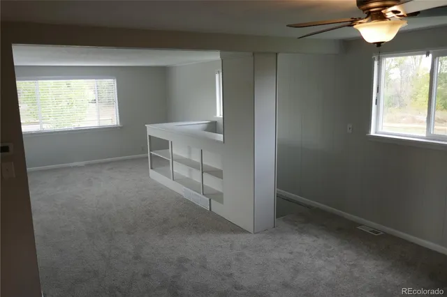 an empty room with windows and fan