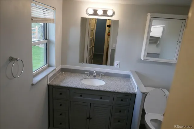 a bathroom with a granite countertop sink vanity and mirror