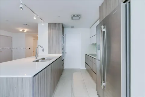 a kitchen with granite countertop a sink and refrigerator