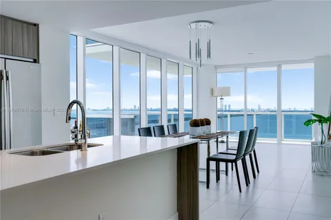 a kitchen with a dining table chairs and refrigerator
