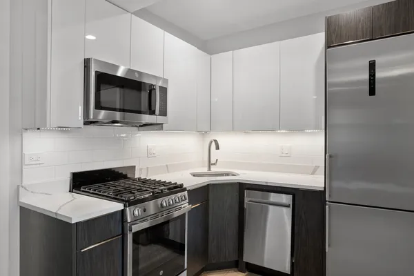 a kitchen with stainless steel appliances a sink a stove a microwave and wooden cabinets