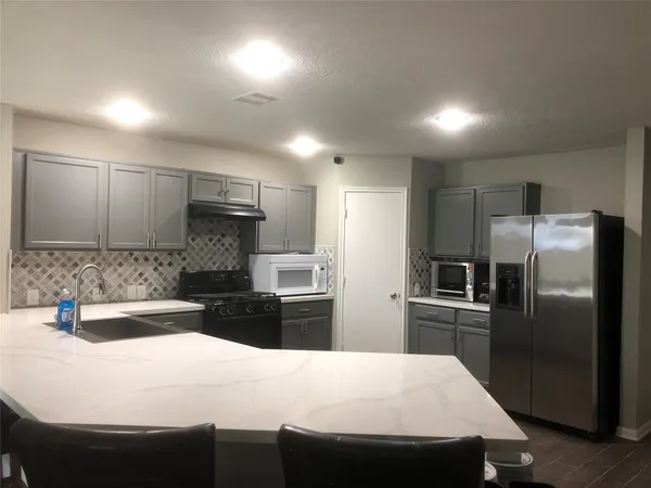 a kitchen with stainless steel appliances kitchen island granite countertop a sink refrigerator and cabinets