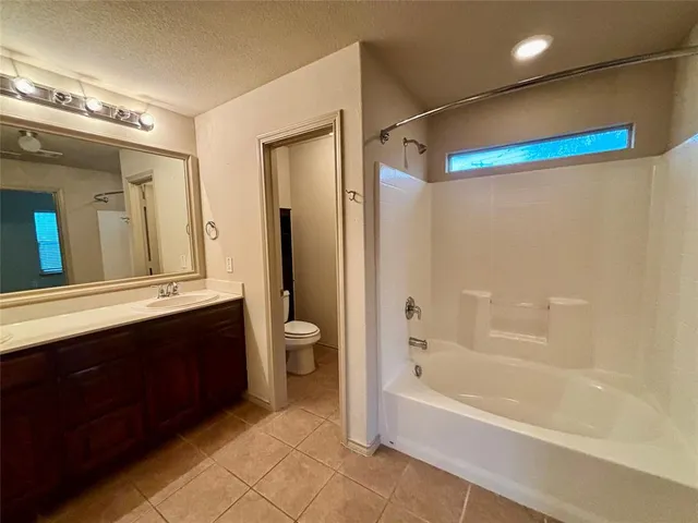 a bathroom with a bathtub shower sink mirror and toilet