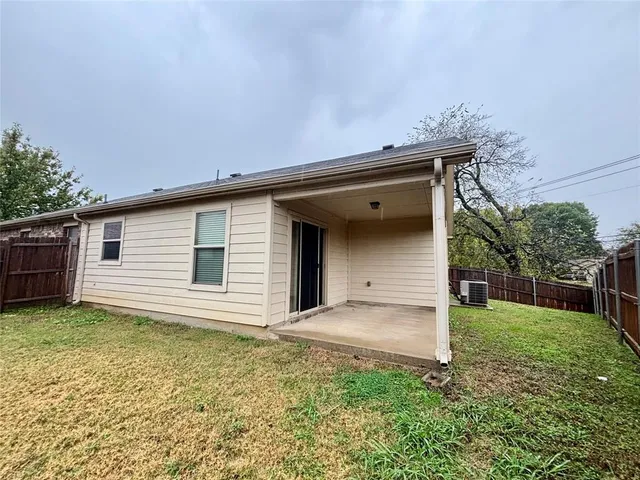 a backyard of a house with plants and large tree