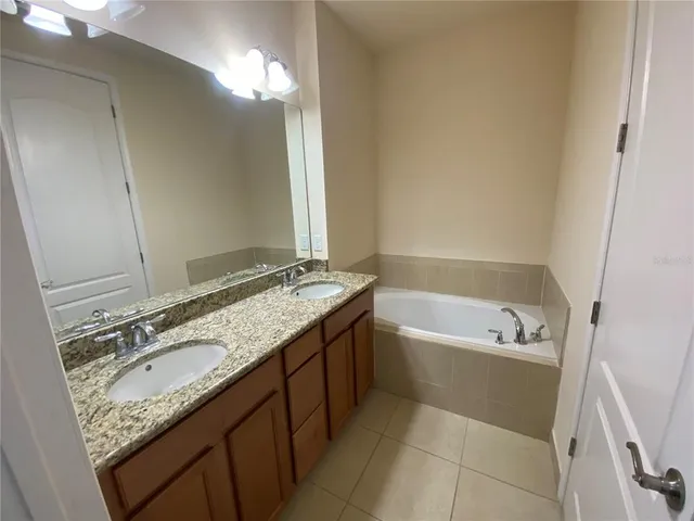 a bathroom with a granite countertop sink a mirror a vanity and a bathtub