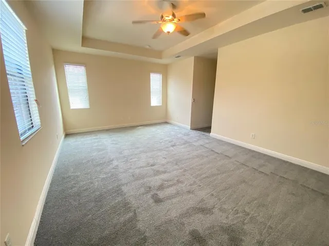 an empty room with windows and fan