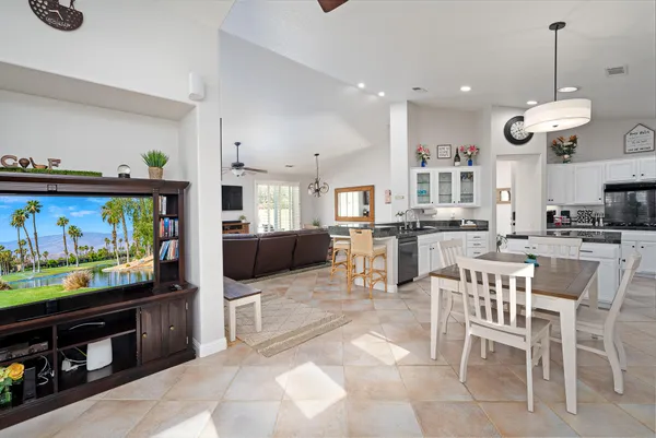 a view of a kitchen with kitchen island stainless steel appliances a stove a table and chairs
