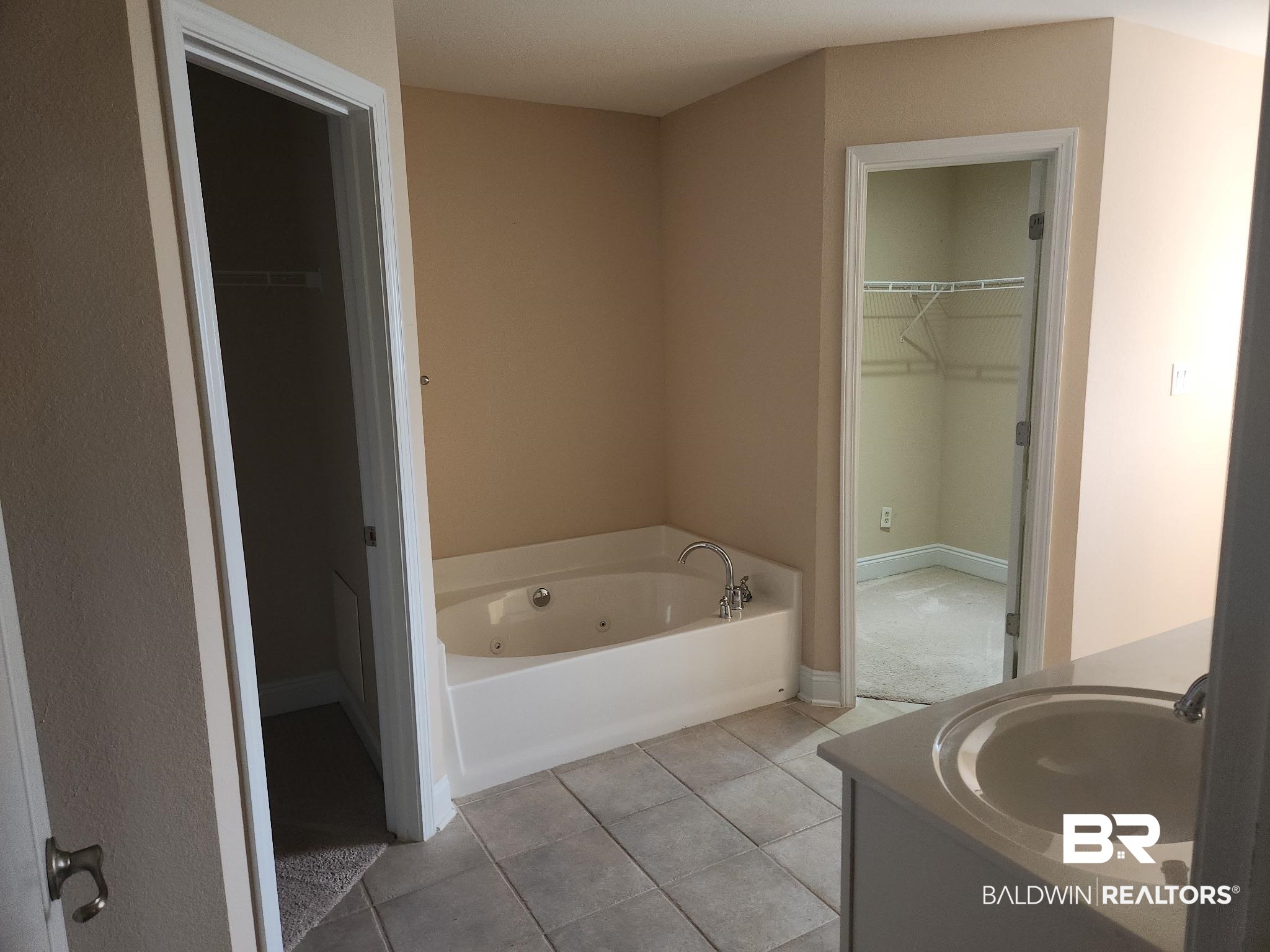 9425 Autauga Bend Daphne, AL 36526 - Photo 10 of 15 Bathroom featuring a spacious closet, vanity, a whirlpool tub, and light tile patterned flooring