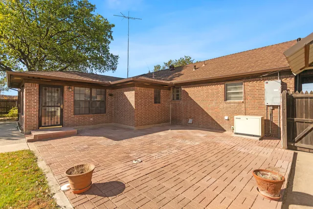 a patio with table and chairs and potted plants