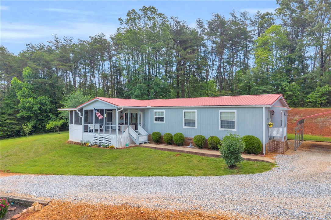 721 Cedar Crest Trail Walhalla, SC 29691 - Photo 3 of 47 Rural retreat with a welcoming screened porch and a vibrant red roof nestled against a forested backdrop.