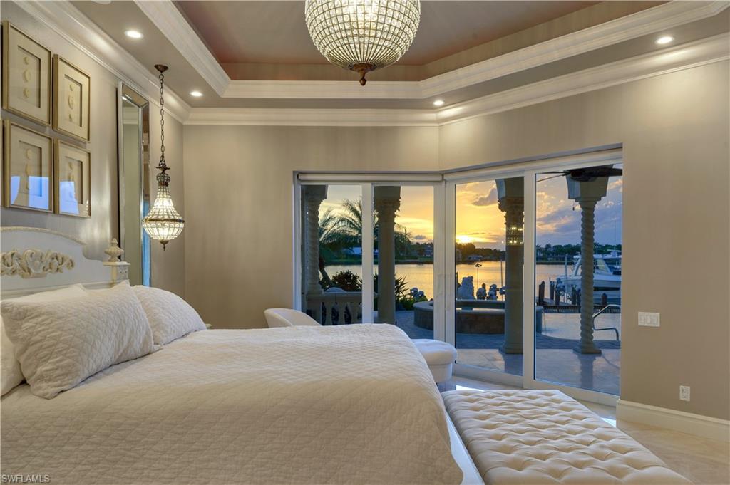 2300 Kingfish Road Naples, FL 34102 - Photo 20 of 36 a bedroom with a large bed and a chandelier