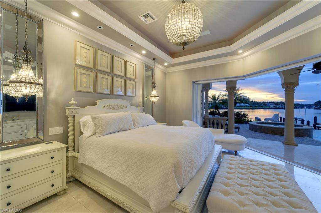 2300 Kingfish Road Naples, FL 34102 - Photo 21 of 36 a bedroom with a large bed and a chandelier