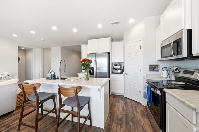 1175 Silver Hollow Road Syracuse, UT 84075 - Photo 12 of 34 Kitchen featuring wood-finish flooring, white cabinetry, stainless steel appliances, and light-toned countertops