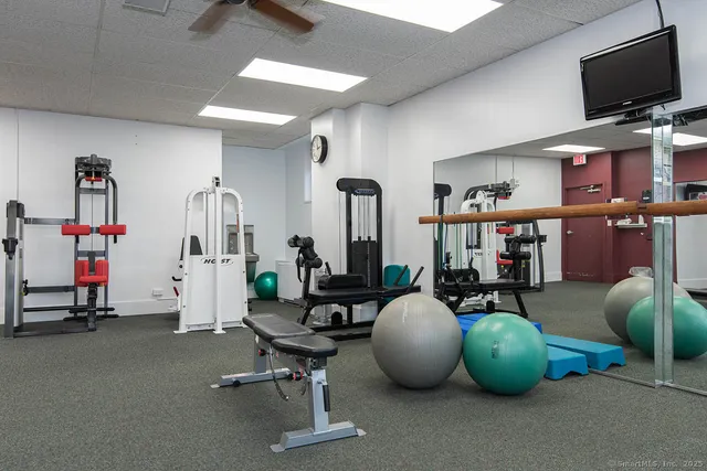 a living room with furniture a flat screen tv and gym equipment