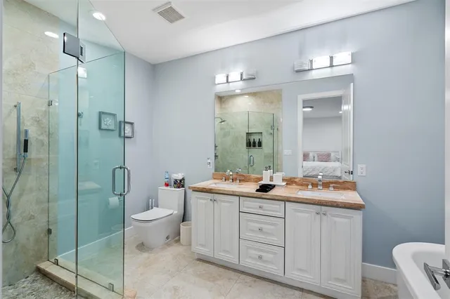 a spacious bathroom with a double vanity sink toilet mirror and shower