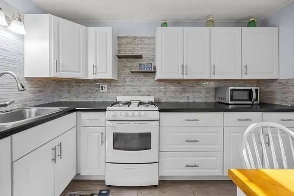 a kitchen with granite countertop white cabinets and white appliances