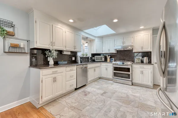 a kitchen with granite countertop white cabinets and stainless steel appliances