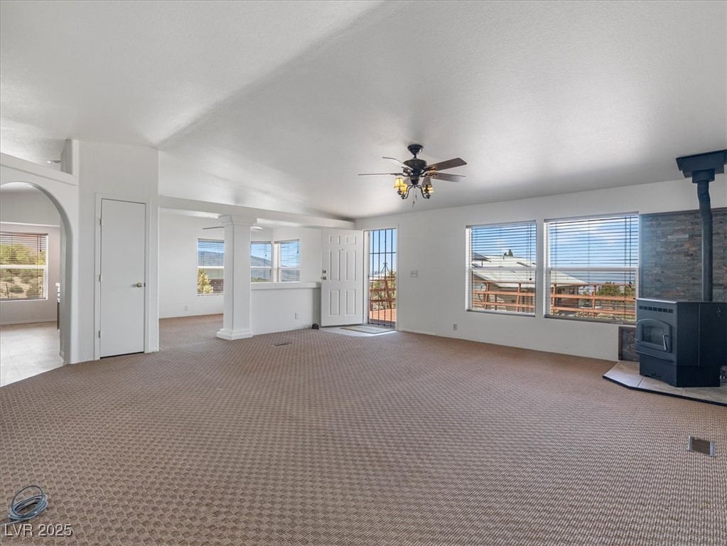 70 West Bonanza Road Las Vegas, NV 89124 - Photo 16 of 71 Unfurnished living room featuring a wood stove, a ceiling fan, carpet floors, and ornate columns