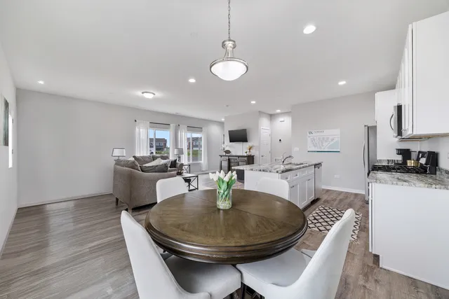 a living room with dining table a couches and kitchen view with wooden floor