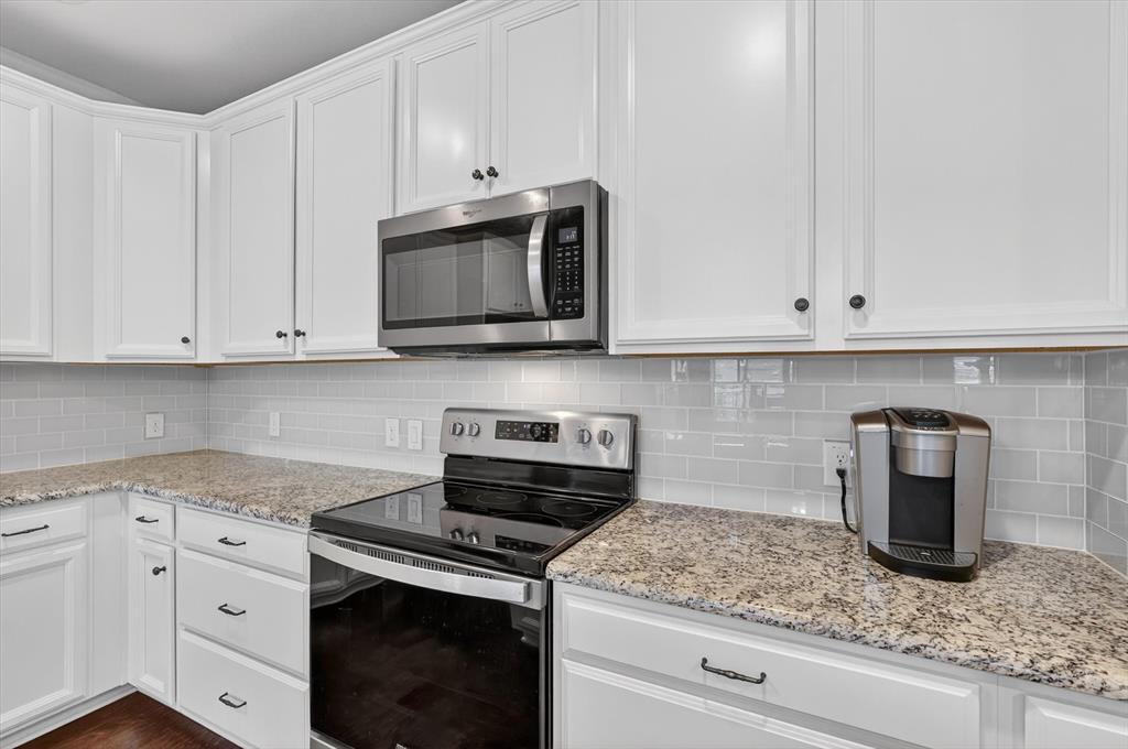 651 Watters Road, Unit 5305 Allen, TX 75013 - Photo 7 of 40 a kitchen with granite countertop white cabinets and stainless steel appliances