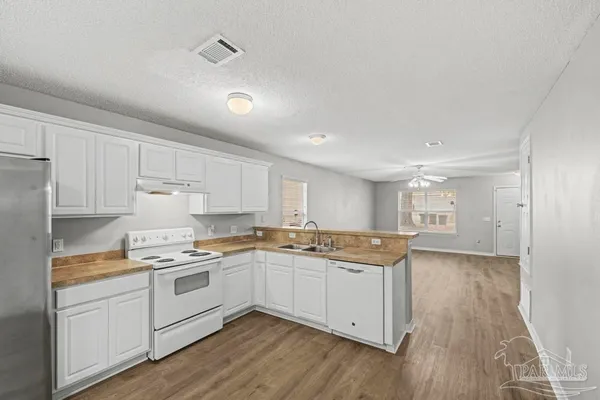 a kitchen with a sink a stove a refrigerator and white cabinets