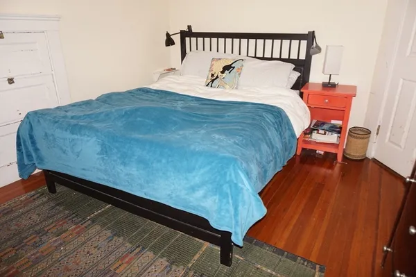 a bed sitting in a bedroom next to a window with wooden floor