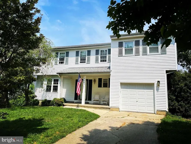 a view of a white house with large windows and a large tree