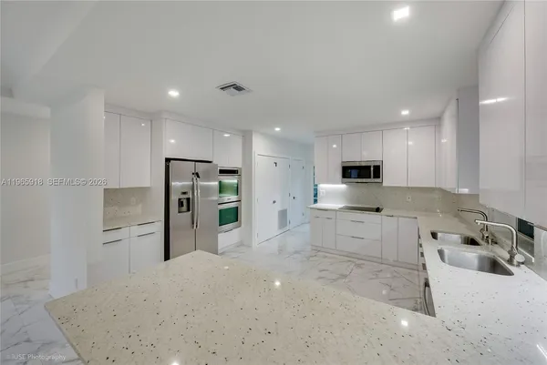 a large kitchen with stainless steel appliances kitchen island granite countertop a refrigerator and a stove top oven