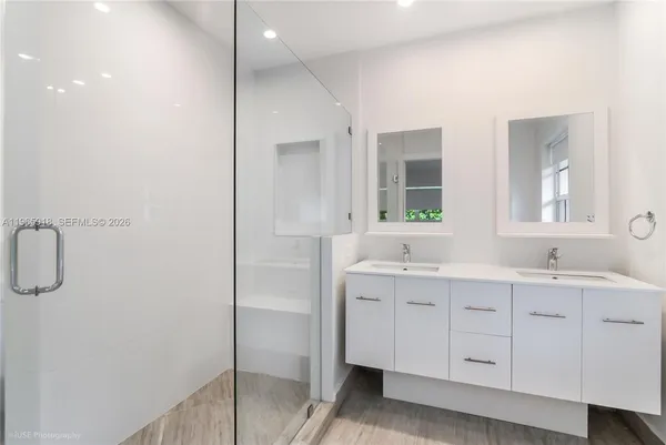 a bathroom with a double vanity sink a mirror and a shower