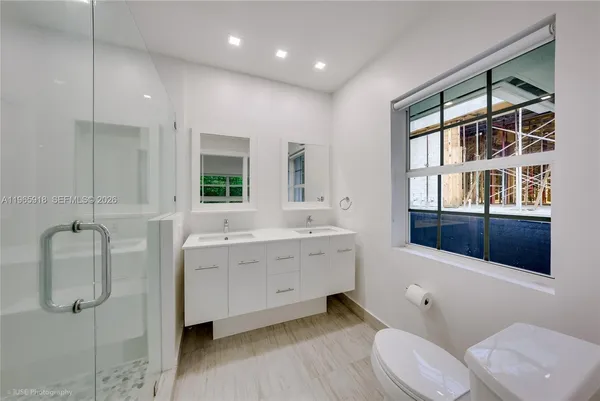 a spacious bathroom with a double vanity sink a toilet and shower