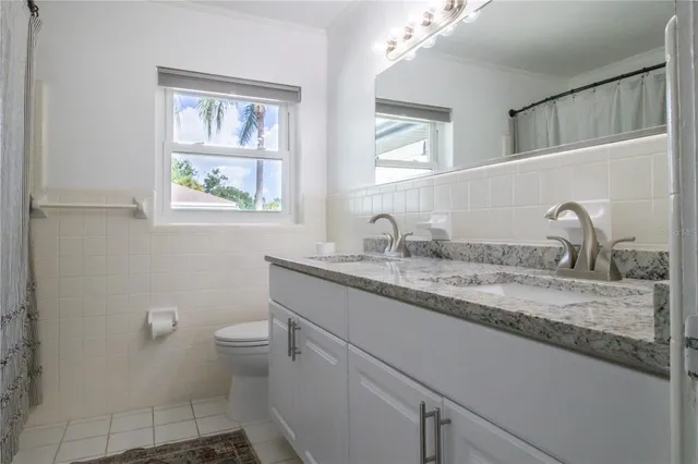 a bathroom with a granite countertop sink a toilet and a mirror