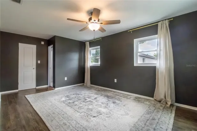 a view of a livingroom with a chandelier fan and wooden floor
