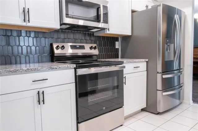 a kitchen with stainless steel appliances granite countertop a stove and a refrigerator with white cabinets