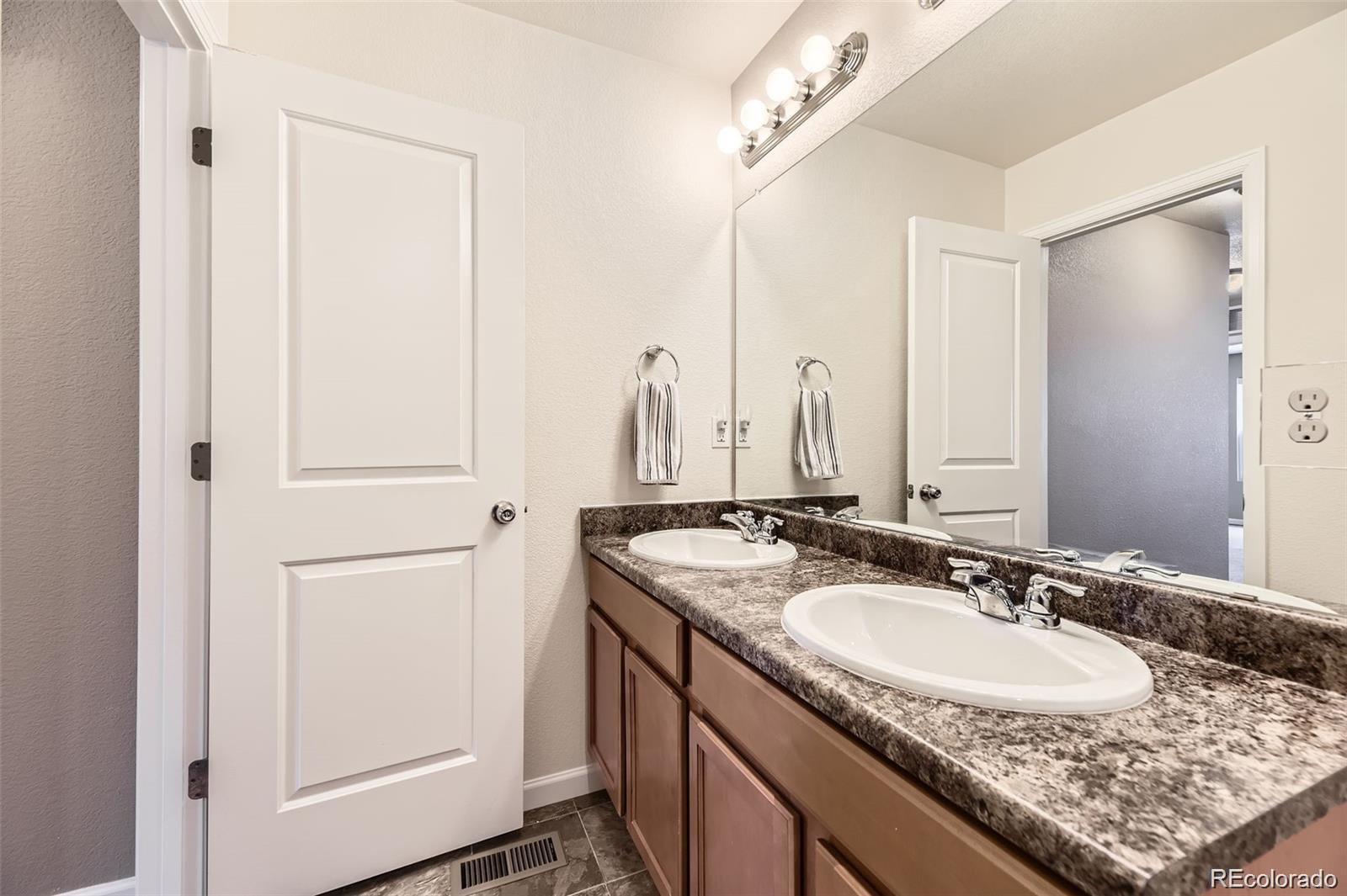 4807 River Highlands Loop Elizabeth, CO 80107 - Photo 21 of 37 a bathroom with a granite countertop sink and a mirror