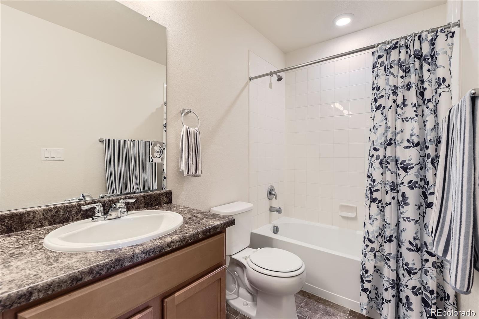 4807 River Highlands Loop Elizabeth, CO 80107 - Photo 22 of 37 a bathroom with a granite countertop sink toilet a mirror a bathtub and shower