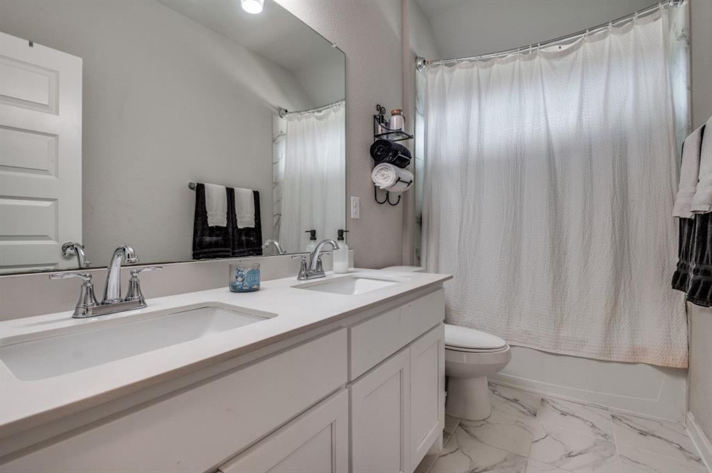153 Arrow Wood Road Waxahachie, TX 75165 - Photo 19 of 29 Full bath with double vanity, marble look tiles, and shower / bath combo