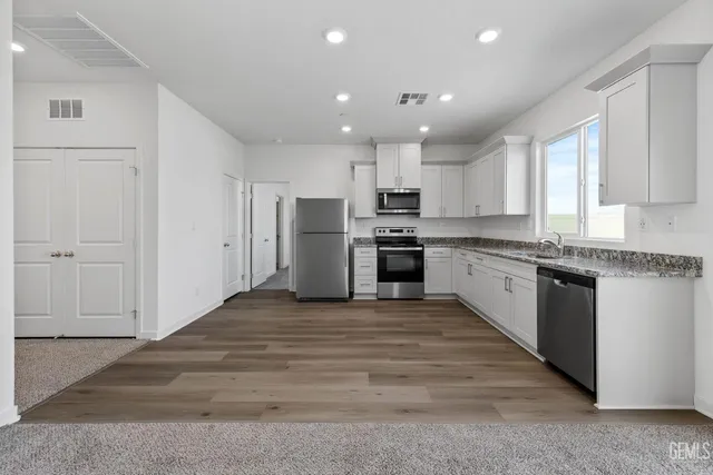a large kitchen with cabinets stainless steel appliances and a window