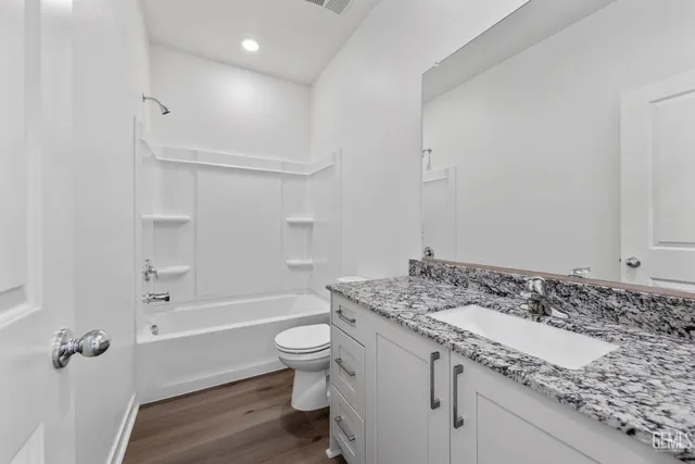 a bathroom with a granite countertop sink a toilet and shower