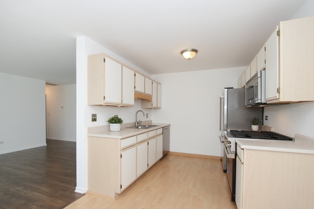 400 Woodview Circle, Unit A Elgin, IL 60120 - Photo 12 of 40 a kitchen with white cabinets a sink stove and refrigerator
