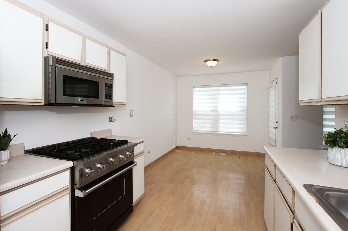 400 Woodview Circle, Unit A Elgin, IL 60120 - Photo 13 of 40 a kitchen with stainless steel appliances a stove a microwave and white cabinets
