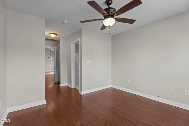 an empty room with wooden floor and a ceiling fan