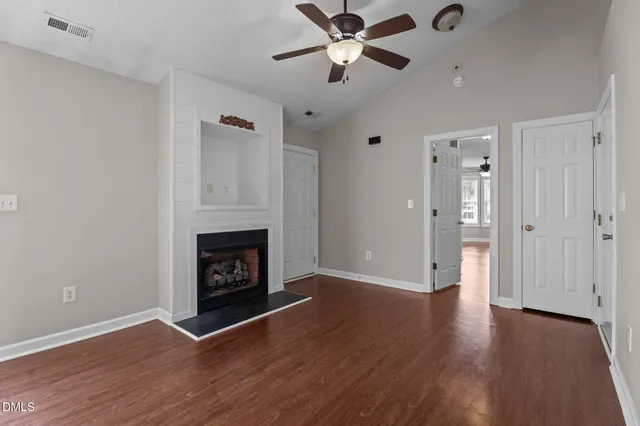a view of an empty room with wooden floor and a fireplace