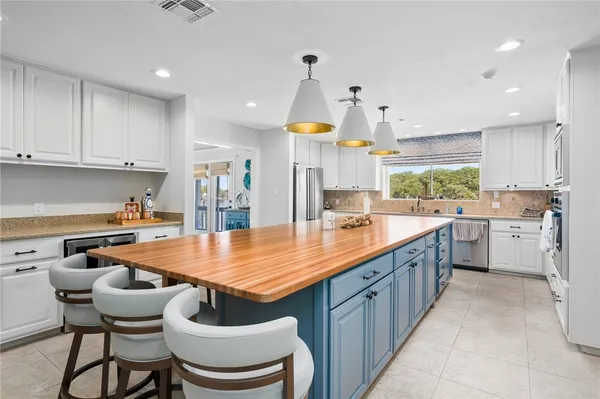 a kitchen with stainless steel appliances granite countertop a table chairs sink and cabinets