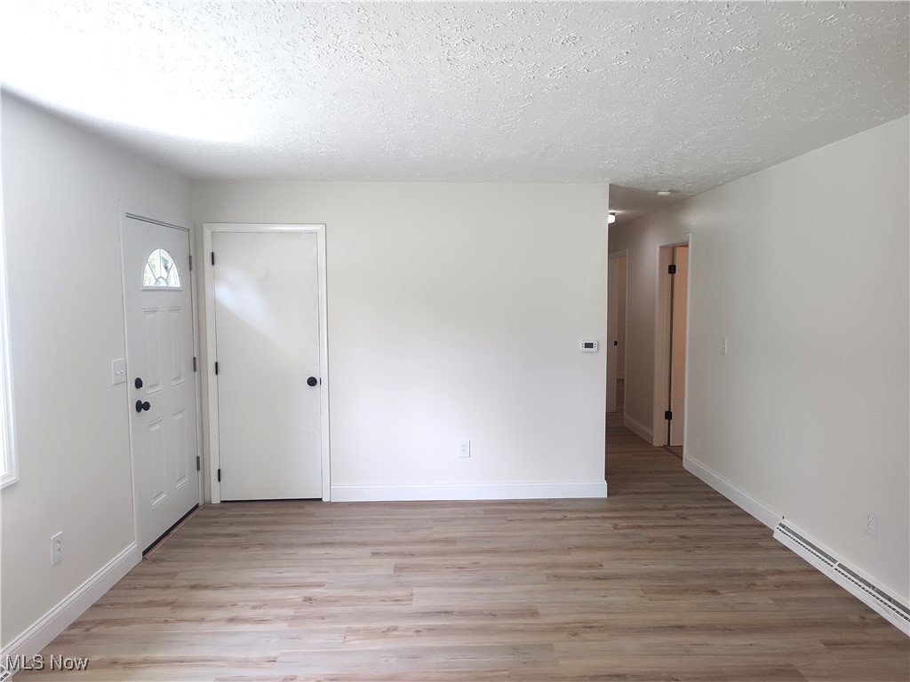 8016 Ninevah Road Geneva, OH 44041 - Photo 19 of 45 Entryway featuring light wood-style flooring, a textured ceiling, and baseboard heating