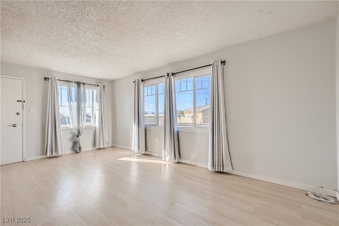 103 West Victory Road Henderson, NV 89015 - Photo 6 of 28 Unfurnished room with a textured ceiling, light wood-style floors, and baseboards
